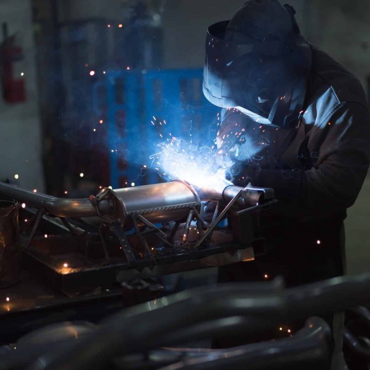 worker-welding-exhaust-pipes-pieces-together.jpg